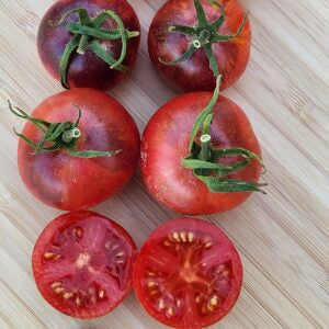 Red tomatoes with green stems on a wooden surface