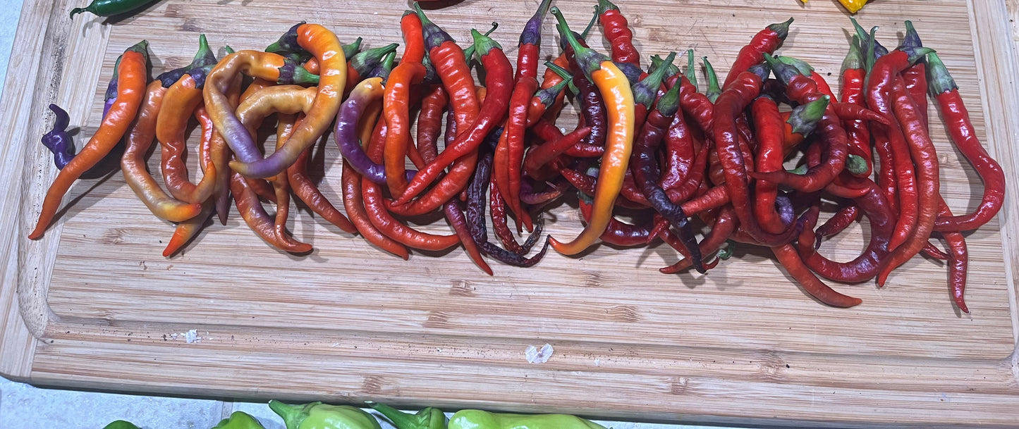 Assorted colorful cayenne peppers on a wooden cutting board
