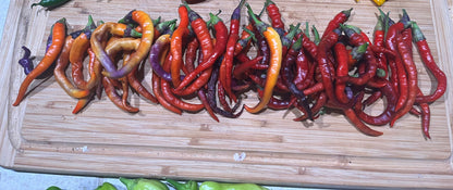 Assorted colorful cayenne peppers on a wooden cutting board