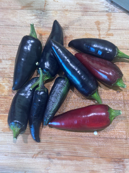 Black and red Czech black jalapeño peppers on a wooden cutting board